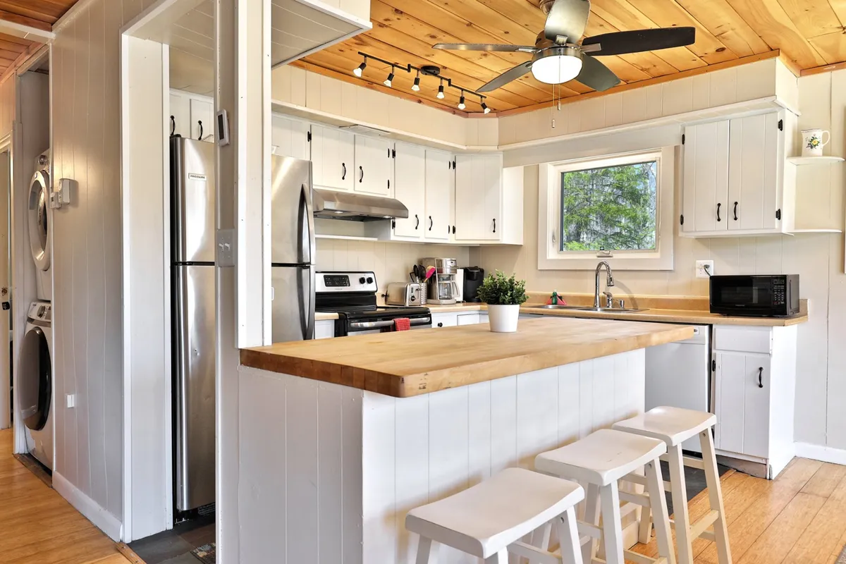 A bright, modern kitchen featuring a spacious island, stainless steel appliances, and a large window with a view, perfect for preparing snacks or drinks before heading out or hosting late-night bites after a night of fun.